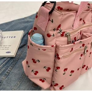 Detail of pink cherry print tote bag with side pocket and blue water bottle