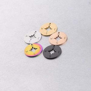 Macro shot of 20mm compass pendant charms in five metallic colors on a textured background