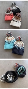 Detailed knit texture and geometric patterns on colorful winter beanies with pom poms