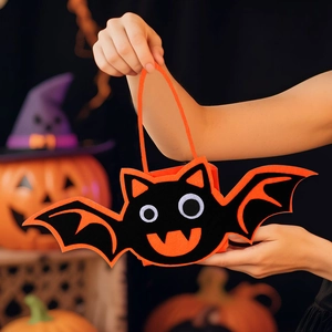 Handheld view of a cute black bat felt candy bag with orange trim for Halloween parties