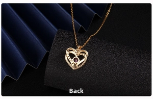 Detailed back view of golden heart pendant with purple zircon on black background