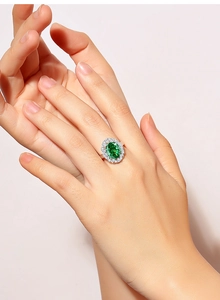Macro detail of oval green emerald ring with silver setting worn on a finger
