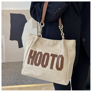 Detail of beige tote bag with HOOTO brown lettering and golden chain leather strap