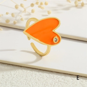 Detail of adjustable gold ring with heart-shaped orange enamel and sparkling zircon