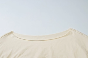 Detailed macro view of the cream boat neck collar and soft knit texture of the top