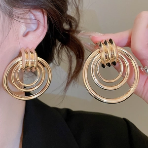 Detailaufnahme goldener mehrlagiger Rundohrringe mit poliertem Metall-Finish