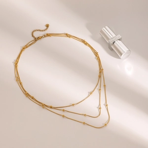 Three-layer gold beaded stainless steel necklace displayed with elegant shadow projection
