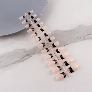 Short square-oval nude press-on nails with black French tips on a display strip