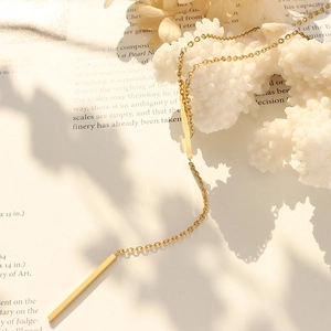 Minimalist 18K gold-plated Y-shaped necklace with geometric bars on a decorative background