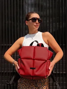 Photo en extérieur d'un sac à dos matelassé rouge avec des sangles noires sur modèle