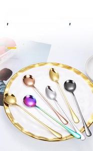 Detailed view of polished colorful stainless steel long handle spoons in a ceramic dish