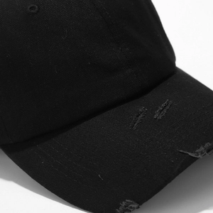 Dettaglio della visiera consumata su cappello da baseball in cotone nero effetto vintage