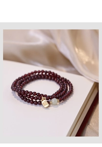 Detailed macro of garnet beaded bracelet with a green jade bead and golden Fu charm