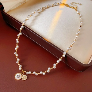 Detail of gold pearl necklace featuring a blue star pendant and snowflake charm
