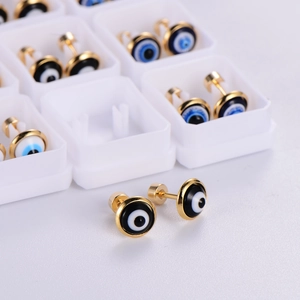 Macro detail of dopamine-themed evil eye stud earrings in gold metal with blue resin