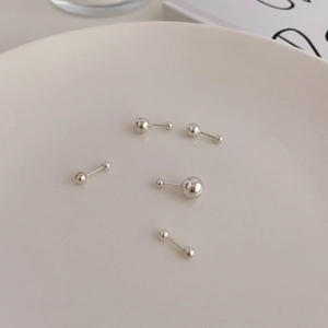 Polished 925 sterling silver ball stud earrings in various sizes on a white ceramic tray