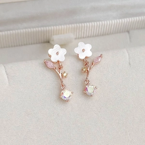 Macro shot of rose gold flower earrings with colorful zircons and shell petals