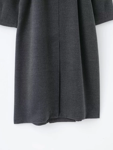 Detailed view of the dark grey wool blend fabric texture and stitching on the coat hem