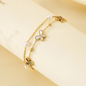 Detail of double-layer stainless steel bracelet with butterfly charms and white pearls