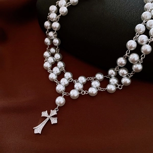 Macro shot of double-layer pearl necklace with a zircon-encrusted silver cross pendant