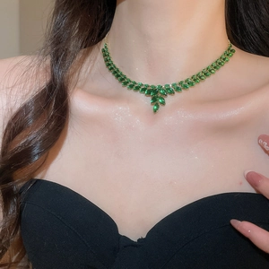 Close-up of gold V-shaped necklace with green marquise-cut zircons worn by a model