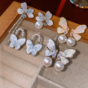 Detailed showcase of asymmetric butterfly pearl tassel earrings with crystal accents