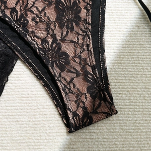 Close-up of black floral lace fabric with nude lining and fine stitching on bikini