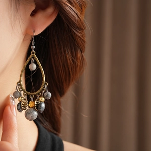 Detail of vintage bamboo style earring with bronze metal and textured beads on model