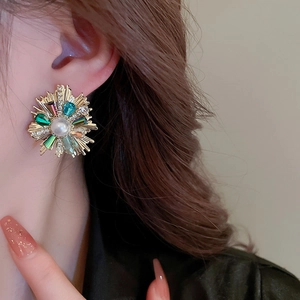 Close-up of sunburst flower earring with white pearl and colorful crystals on model
