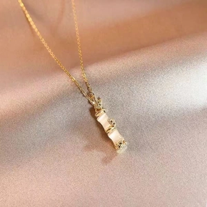 Detailed close-up of golden bamboo necklace with elegant white stone inlay on silk