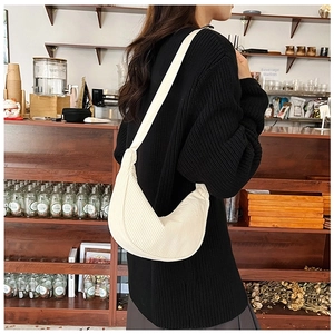 Detail showing the pleated corduroy texture and crescent shape of the white shoulder bag