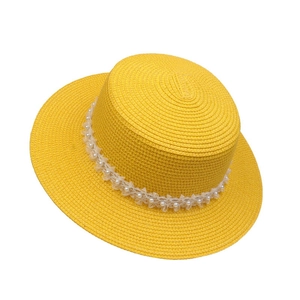 Detail of yellow straw hat with white lace trim and pearls for summer sun protection