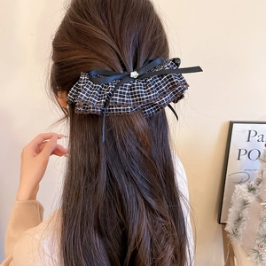 Detailed close-up of a checkered bow hair clip styled on hair, showing elegant fabric texture