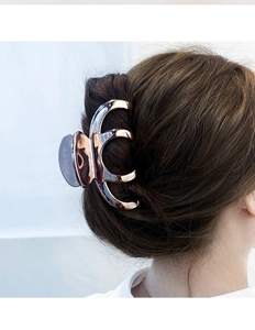 Close-up of a large rose gold metal hair claw clip holding a stylish bun hairstyle