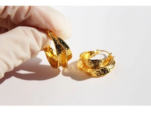 Detailed close-up of golden hoop earrings featuring a handcrafted hammered metal texture