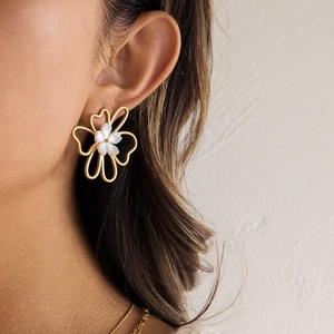 Close-up of 18K gold stainless steel flower earrings with white pearl detail on model