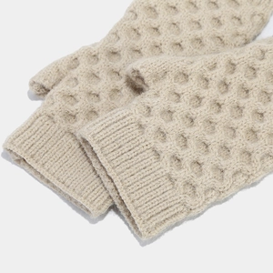 Close-up of beige knitted fingerless gloves showing honeycomb texture and ribbed cuffs