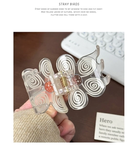 Detailed close-up of a transparent butterfly hair claw clip with orange dot patterns