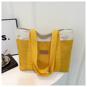 Detail of minimalist canvas tote bag in ginger yellow and cream white on a white stand