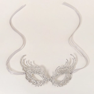 Macro detail of silver rhinestone masquerade mask featuring intricate cutout wing patterns