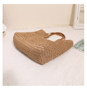 Close-up of woven straw handbag with brown leather straps for summer beach style