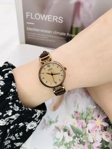 Detailed shot of a vintage gold women's watch with brown leather strap and small dial