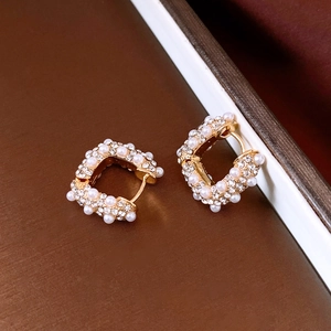 Détail des boucles d'oreilles Huggie en forme de U plaquées or 18k avec perles et strass