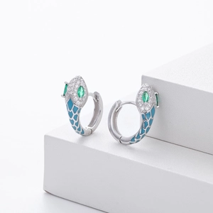 Detailed view of silver snake hoop earrings with blue enamel scales and green gemstone eyes