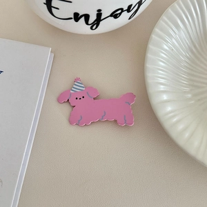 Detail of pink cartoon dog hair clip with a blue striped party hat on a beige background