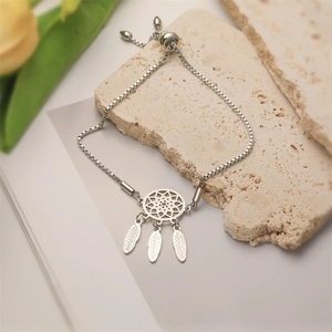 Detail eines Dreamcatcher-Armbands mit Federn und verstellbarer Boxkette auf Stein
