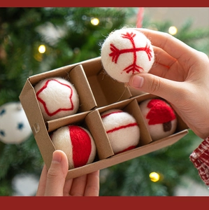 Close-up of handmade wool felt Christmas ornaments in a minimalist kraft gift box