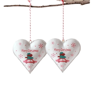 Pair of heart-shaped metal Christmas ornaments with Merry Christmas prints on tree branch