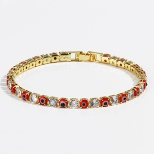Detail of gold tennis bracelet with red evil eye charms and sparkling zircon stones