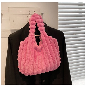 Detailed texture of pink plush tote bag with vertical stripes over a black suit